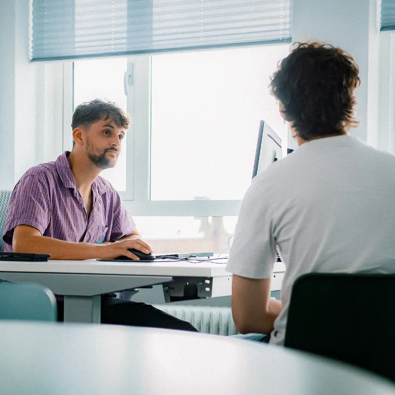 Behandelaar en cliënt zijn met elkaar in gesprek aan een bureau